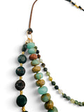 A multi-strand beaded necklace featuring dark green faceted forest jasper stone beads, light ocean jasper beads, bloodstone coin beads separated by small gold spacer beads, suspended on leather cord against a white background.