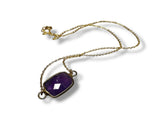 Gold necklace with a purple Amethyst gemstone pendant on a white background
