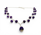 Necklace with purple beads and a  pendant on a white background. Amethyst Drop Statement Sterling Necklace.
