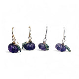 Set of four purple pumpkin-shaped earrings on a white background