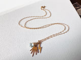 Necklace with hand and lightning bolt charms on a white fabric background