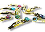Gold hair clips with colorful gemstones on a white background