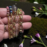 Assorted chain gemstone stretch bracelets against a floral backdrop. 