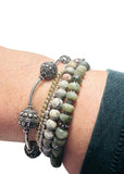 Stack of beaded bracelets on a wrist with a white background