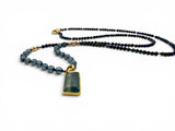 Necklace with blue beads and a green pendant on a white background