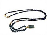 Necklace with dark beads and gold clasp on a white background