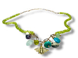 Necklace with green beads and a bee charm on a white background