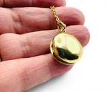 Gold locket held in a hand against a white background. Blue Enamel Locket Opened Back View.