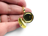 Gold locket held in a hand against a white background. Blue Enamel Locket Opened.