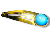 Gold hair clip with a blue gemstone on a white background