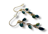 Gold and green beaded earrings on a white background
