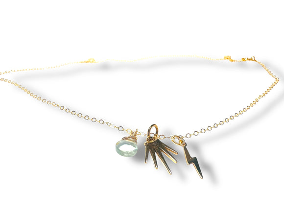 Gold necklace with hand and lightning bolt charms on a white background