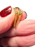 Gold hoop earrings being held between fingers with red glittery nail polish.