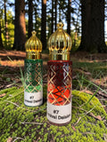 Two decorative perfume bottles labeled '#7 Carnival Daisies' standing on moss in a forest setting. One bottle is green with gold detailing and the other is red with gold detailing, both topped with ornate gold caps.