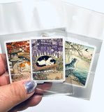 Set of stickers with cat illustrations held by a hand against a white background