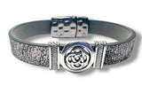 Bracelet with gray leather strap and silver Celtic knot design on a white background