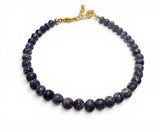 Necklace with purple beads and a gold clasp on a white background
