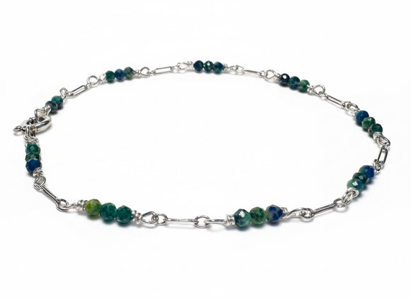 Silver bracelet with green beads on a white background