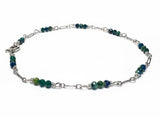 Silver bracelet with green beads on a white background