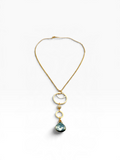 A gold chain necklace featuring three stacked circular gold rings, a small gold bead, and a dangling teardrop-shaped blue-green stone pendant, shown on a clean white background.