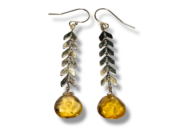 Pair of earrings with leaf-like designs and amber-colored beads on a white background