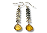 Pair of earrings with leaf-like designs and amber-colored beads on a white background