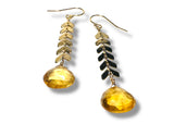 Pair of earrings with yellow teardrop-shaped beads and gold and black leaf-like designs on a white background.