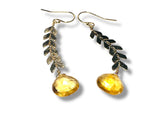 Pair of earrings with leaf-like designs and yellow Citrine gemstones on a white background