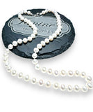 Classic Pearl Necklace -white pearls knotted on silk shown on black slate circle with my logo etched onto it.