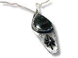 Silver pendant with black stone on a white background