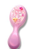 Pink hairbrush with glittery pink handle and bristles on a white background