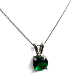 A silver pendant necklace featuring a round-cut dark green gemstone in a four-prong setting, suspended from a delicate silver chain against a plain white background.