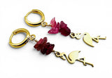 Gold earrings with pink gemstones and flamingo charms on a white background