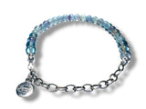 Blue beaded bracelet with a silver chain and charm on a white background