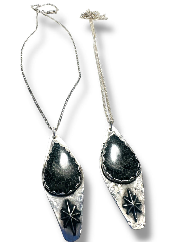Two silver necklaces with black stone pendants on a white background