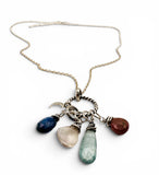 Necklace with various colored stones and charms on a white background