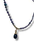 Beaded necklace with a gold chain and blue pendant on a white background