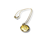 Gold necklace with a round pendant on a white background