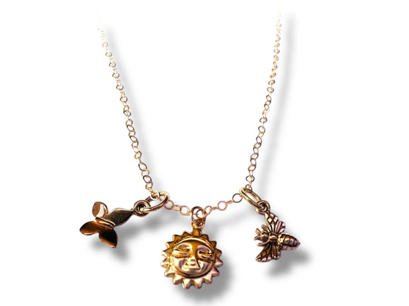 Gold necklace with butterfly, sun, and bee charms on a white background
