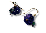 Pair of purple flower-shaped pumpkin earrings with gold accents on a white background