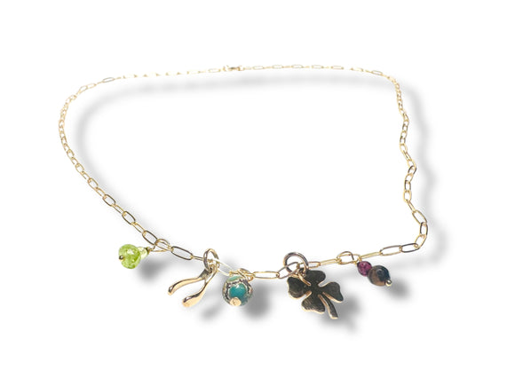 Gold necklace with various charms on a white background
