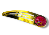 Gold hair clip with a pink gemstone on a white background