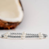 Silver beaded bracelet with pearls on a light background