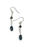 A pair of silver drop earrings featuring a dark green teardrop-shaped bead, a small dark green bead, and a short chain of silver links.