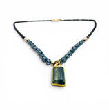 Necklace with blue beads and a green pendant on a white background
