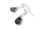 Silver earrings with dark stone drops on a white background