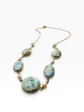 A gold-tone beaded necklace featuring light blue and white marbled stone beads, displayed on a clean white background.