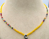 A beaded necklace displayed on a beige jewelry bust. The necklace features a bright yellow beaded center section, side sections of small multicolored beads, and a polished silver letter 'C' pendant at the bottom center.
