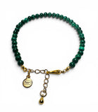 Green beaded bracelet with gold clasp and tag on a white background