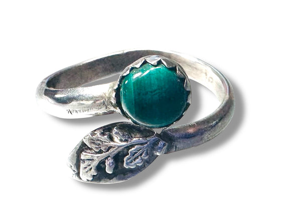 Silver ring with a green stone on a white background